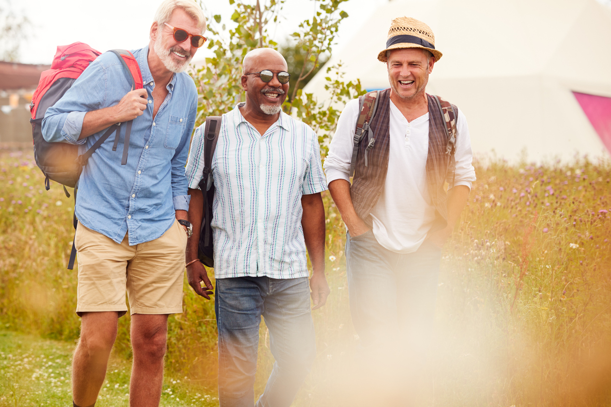 Group Of Mature Male Friends Walking Along Path Through Yurt Campsite